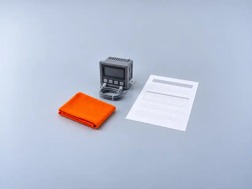 Contador de ciclos digital numa pequena chapa, com o cabo cinza enrolado, ao lado de um certificado de calibração