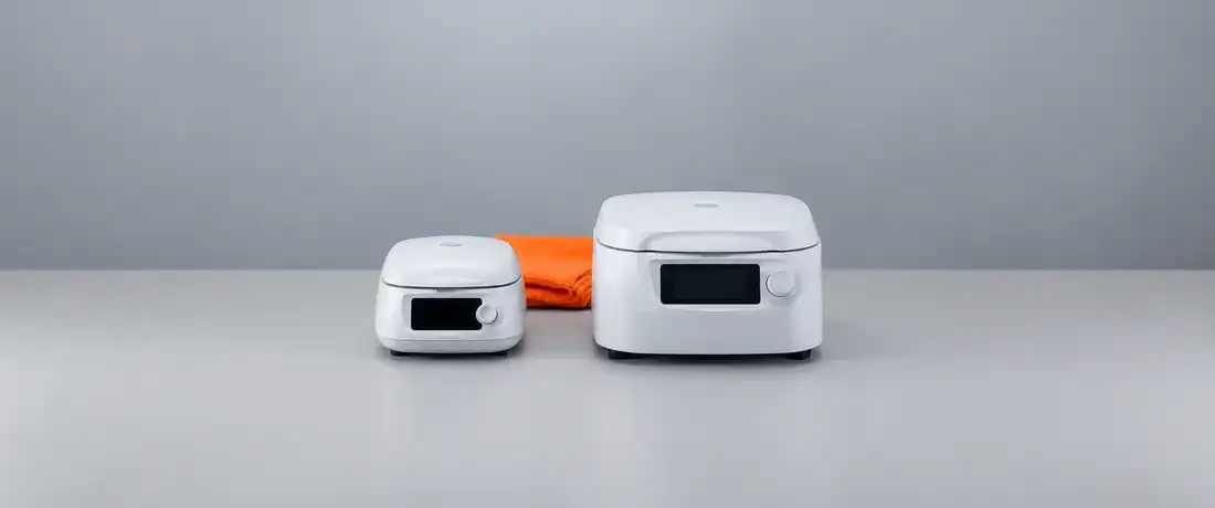 Uma microcentrífuga pequena e uma centrífuga de bancada maior, fechadas, lado a lado e de frente sobre a bancada