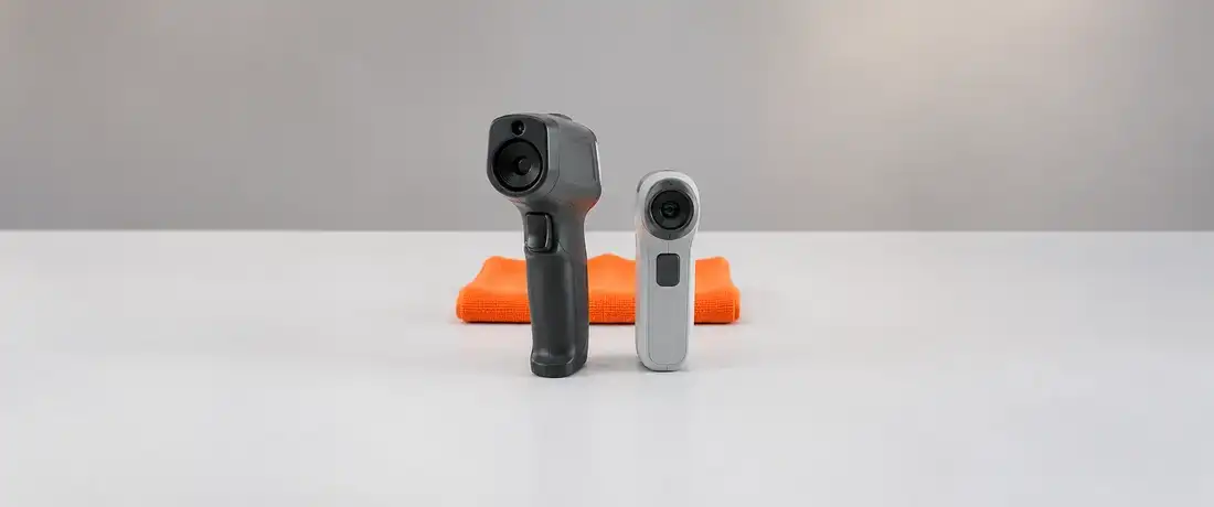 Dois pirômetros portáteis de modelos diferentes, um em pistola e outro compacto, lado a lado com as lentes à frente