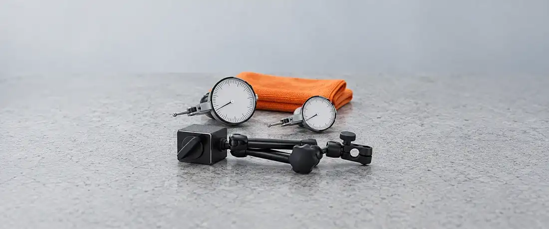 Dois relógios apalpadores de tamanhos diferentes lado a lado, com um suporte magnético à frente, sobre a mesa de granito